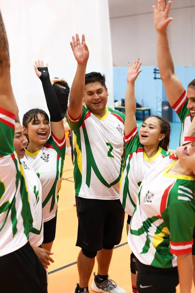 A tournament team in matching jerseys raising their hands together