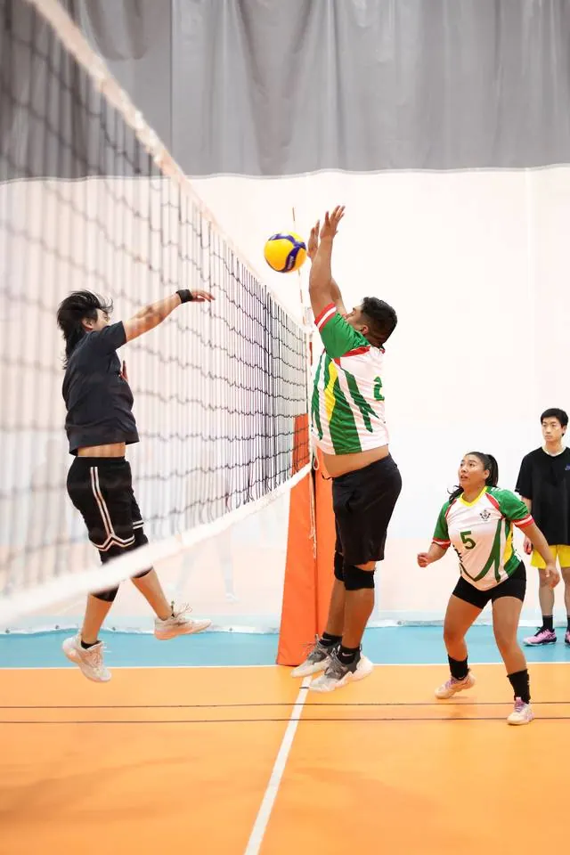 A blocker going up against a hitter at the net
